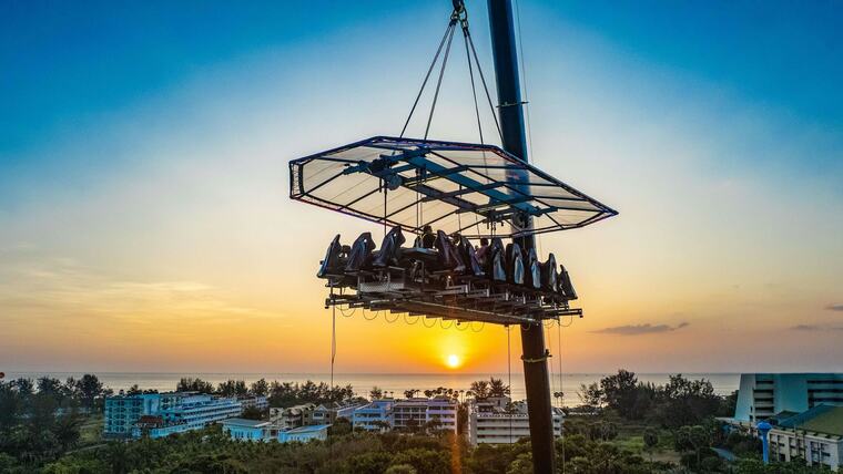 Платформа Dinner in the Sky с гостями на высоте 50 метров над Кароном, солнце садится в море