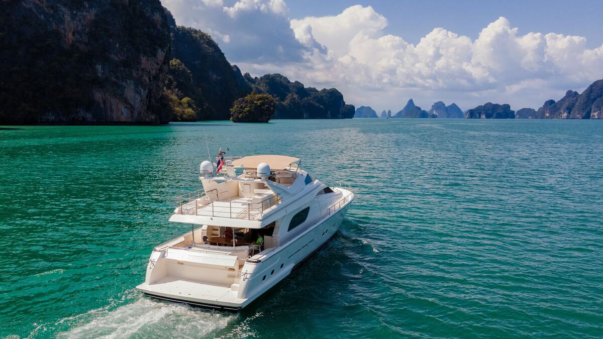 Яхта Ferretti 80 Sofia идёт по морю, за ней скалистые острова