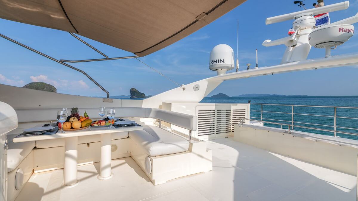 Флайбридж яхты Ferretti 80 Sofia под тентом: стол с фруктами и диваны