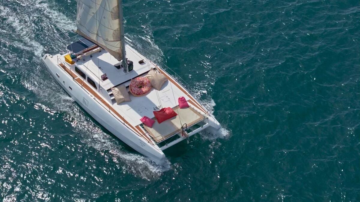 Парусный катамаран Sweet 46 идёт по морю — вид сверху на палубу с подушками