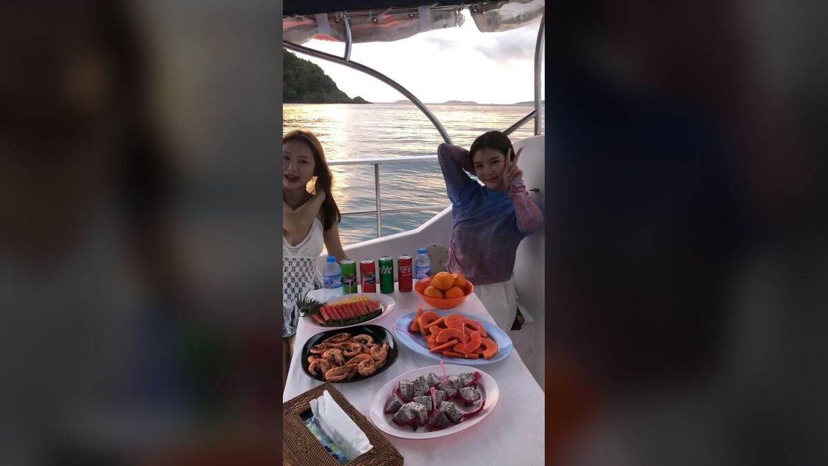 Гостьи у стола с фруктами и морепродуктами на катамаране Sweet 46 на закате